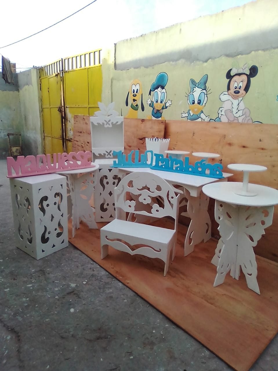 Conjunto de mobiliário branco para criança, com um banco, mesas de apoio e recortes decorativos ornamentados.