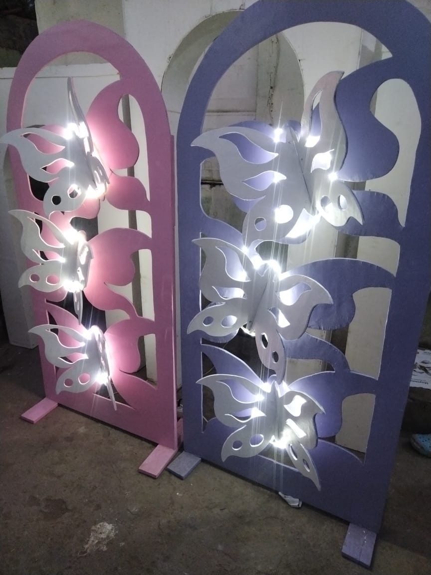 Dois painéis decorativos em arco, um rosa e um roxo, com borboletas recortadas e iluminadas a LED.
