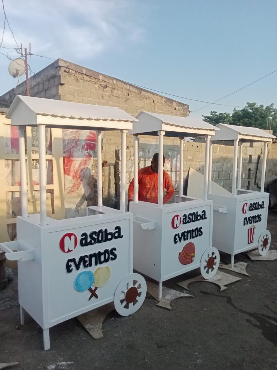 Três quiosques brancos em madeira, com telhado de ripas e sinalética Nasoba Eventos, alinhados ao ar livre.